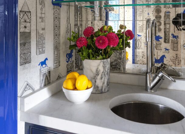 A blue and white bar with custom chrome bar rods and a marble counter top. blue and white Jennifer Shorto horse wallpaper adorns the walls of a wet bar leading into a blue and pink dining room by jewel Marlowe. Luxury design, colorful design, famous designer, washington dc, virginia, maryland